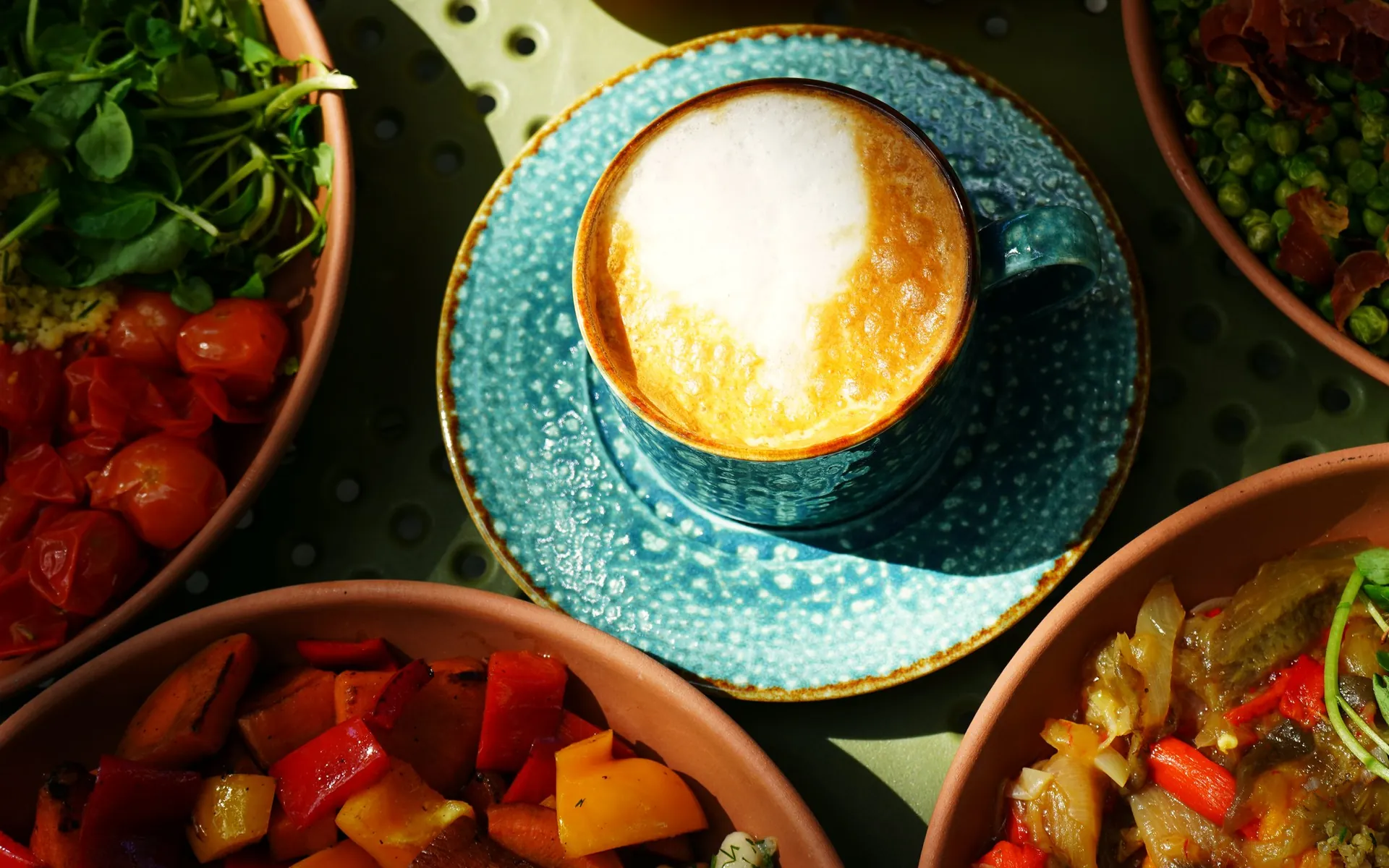 Café con leche y bowls de Fresora sobre una mesa al sol