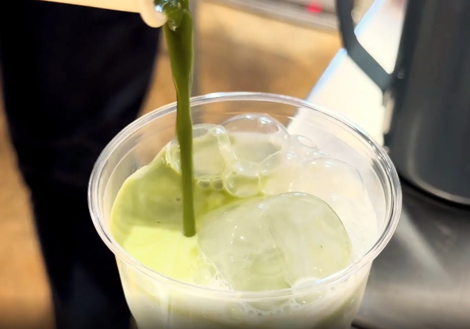 Matcha vertiéndose sobre leche con hielo